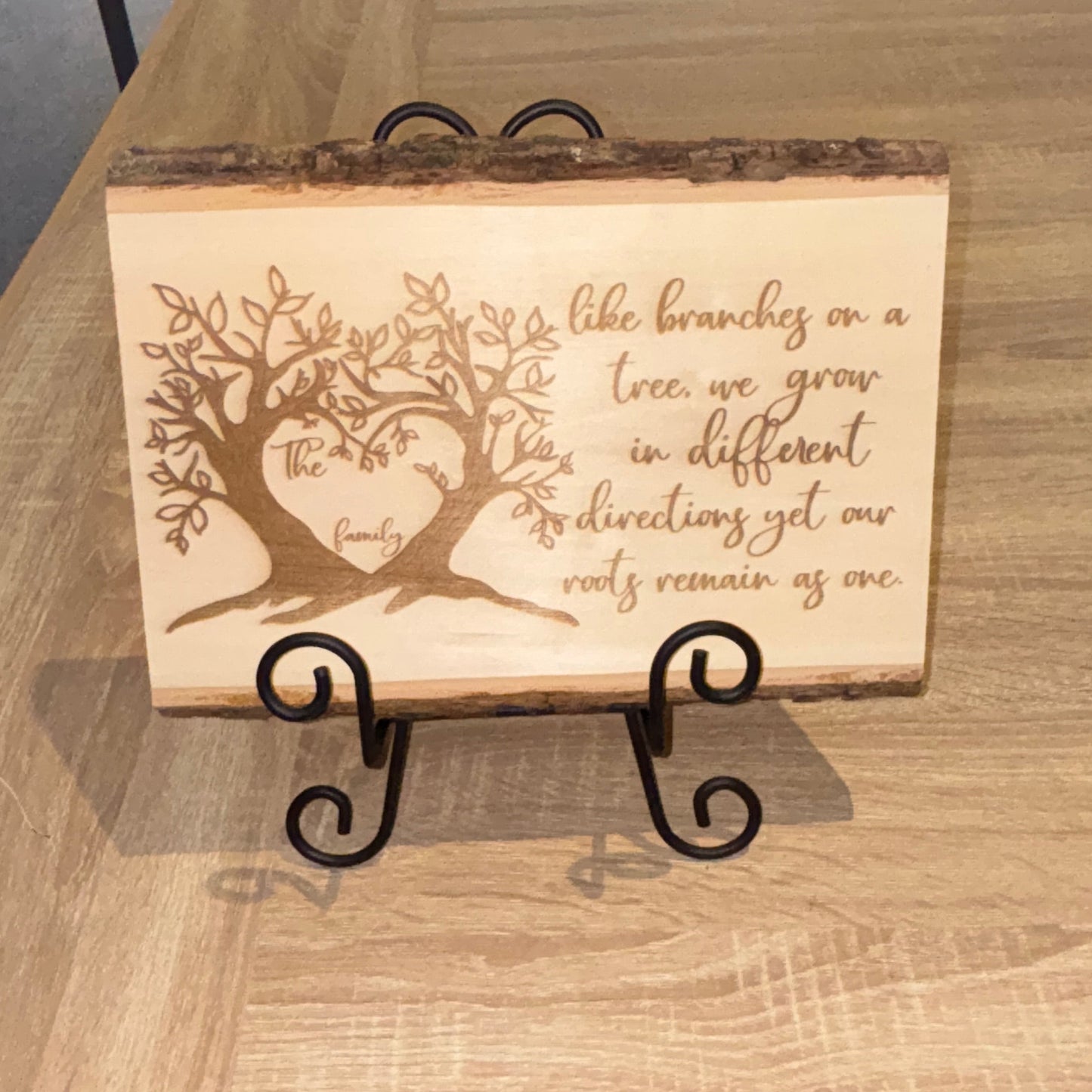 Wooden sign with engraved design and text on a wooden surface