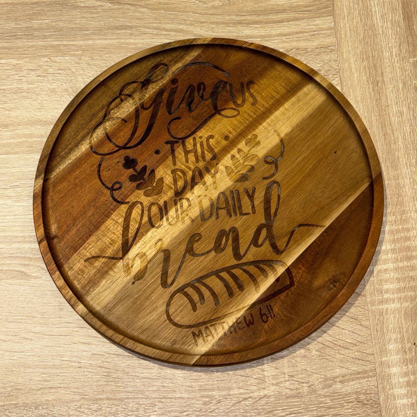 Wooden serving tray with engraved text on a wooden surface