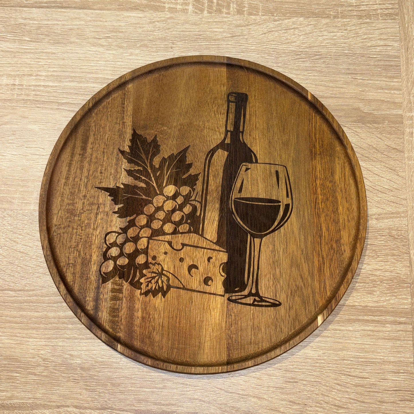 Wooden round tray with wine-themed engraving on a wooden surface