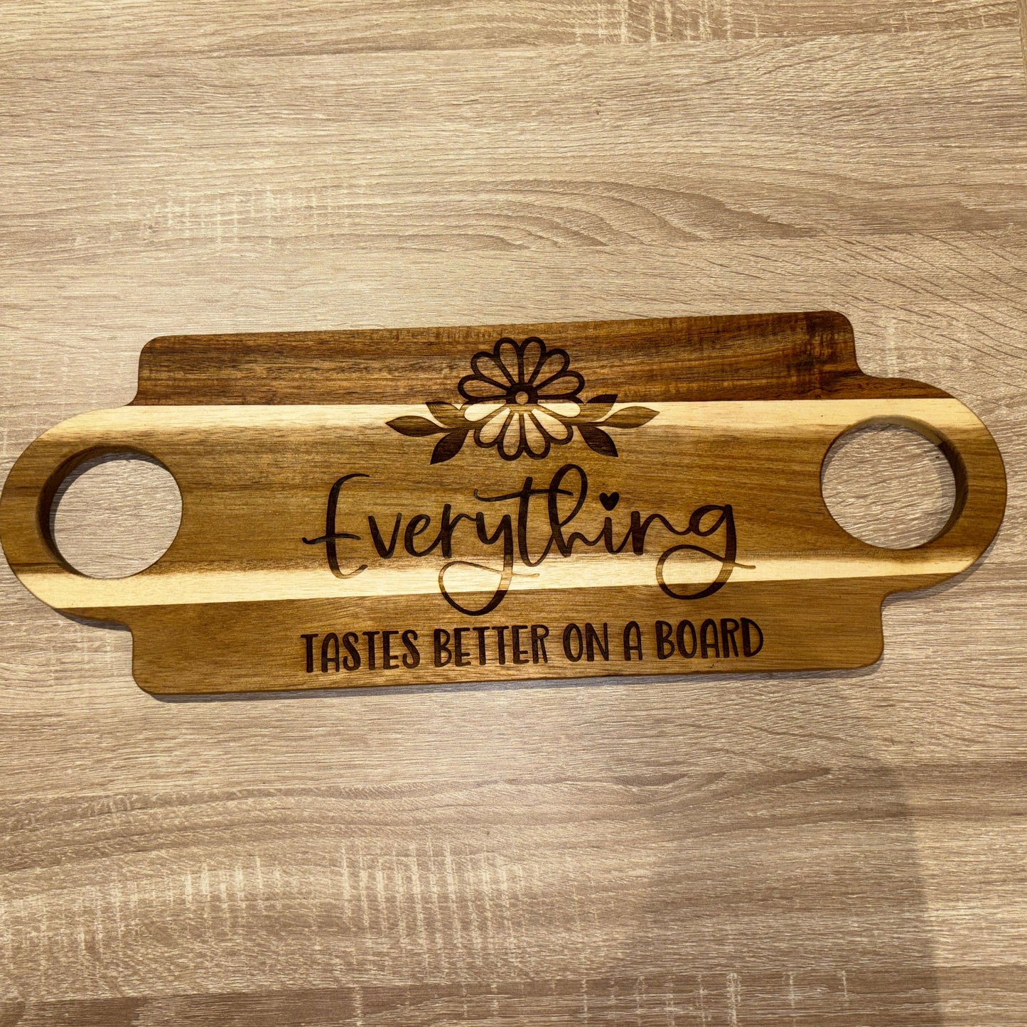 Wooden serving board with engraved text on a wooden surface