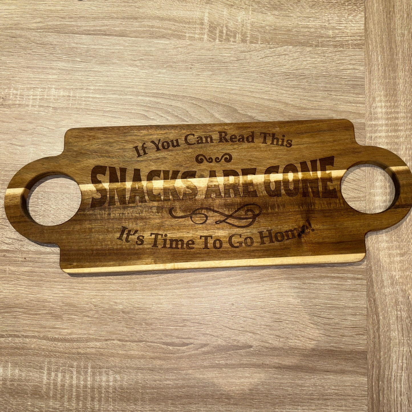 Wooden serving board with engraved text on a wooden surface