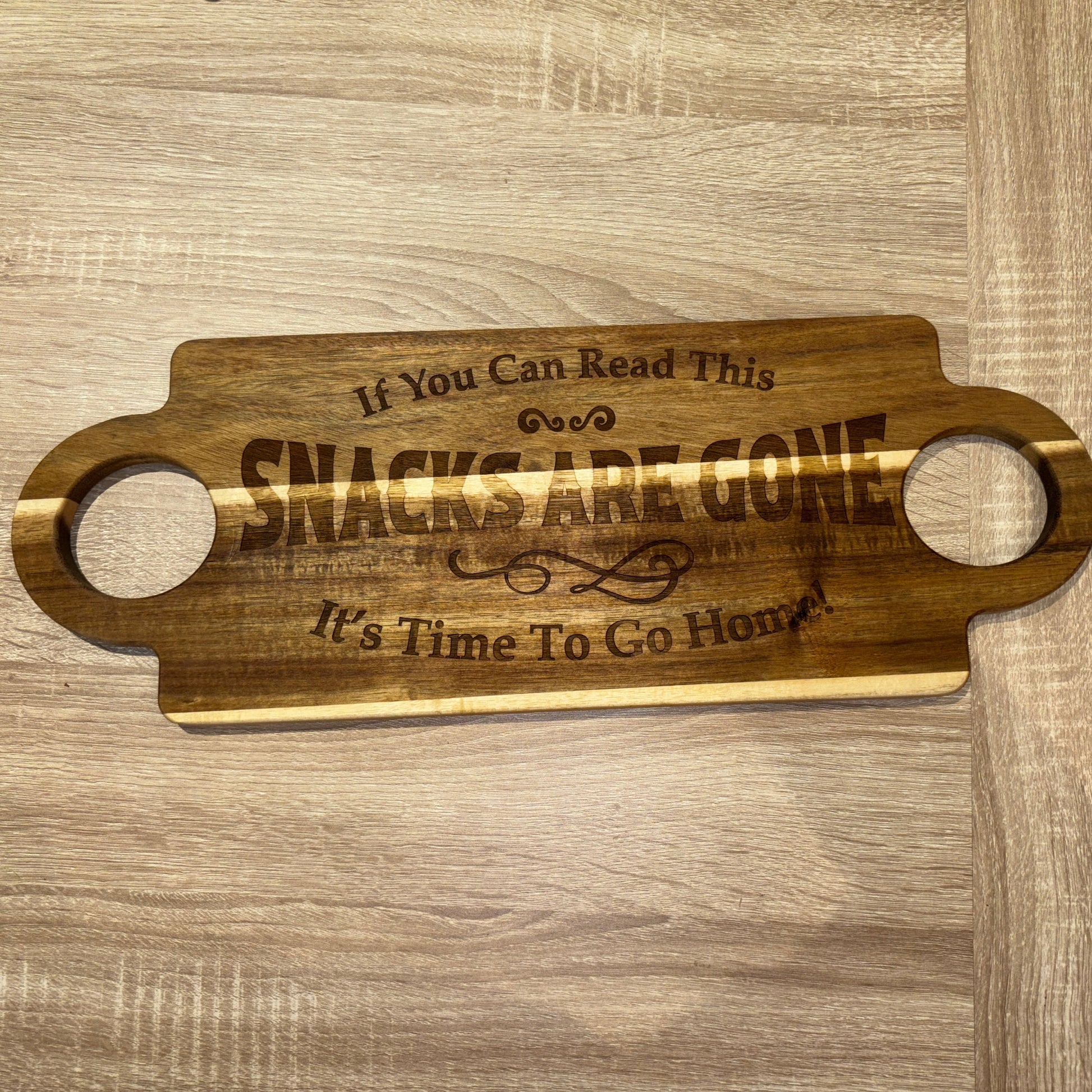 Wooden serving board with engraved text on a wooden surface